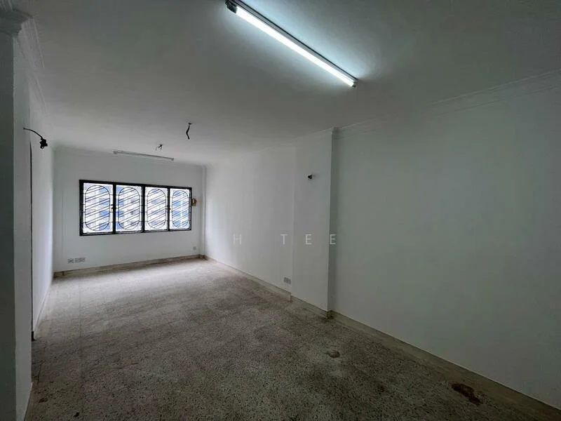 Room features: white painted walls, polished concrete flooring, fluorescent ceiling lights, three windows with metal grilles, no visible furniture or decor, empty space.