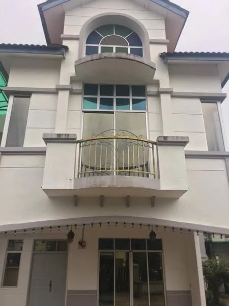 Exterior type: detached bungalow; features: white painted facade, arched windows, balcony with metal railing, flat roof, two-storey structure, large glass windows, decorative elements above windows, porch area with overhang; style: modern.