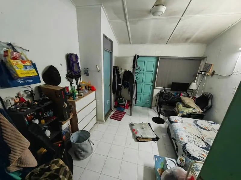 Room features: white painted walls, tiled flooring, ceiling fan, single bed with floral bedding, black leather sofa, small desk with monitor, dresser with multiple drawers, clothing rack, window with blinds, area rug, wall-mounted light, various personal items on surfaces.