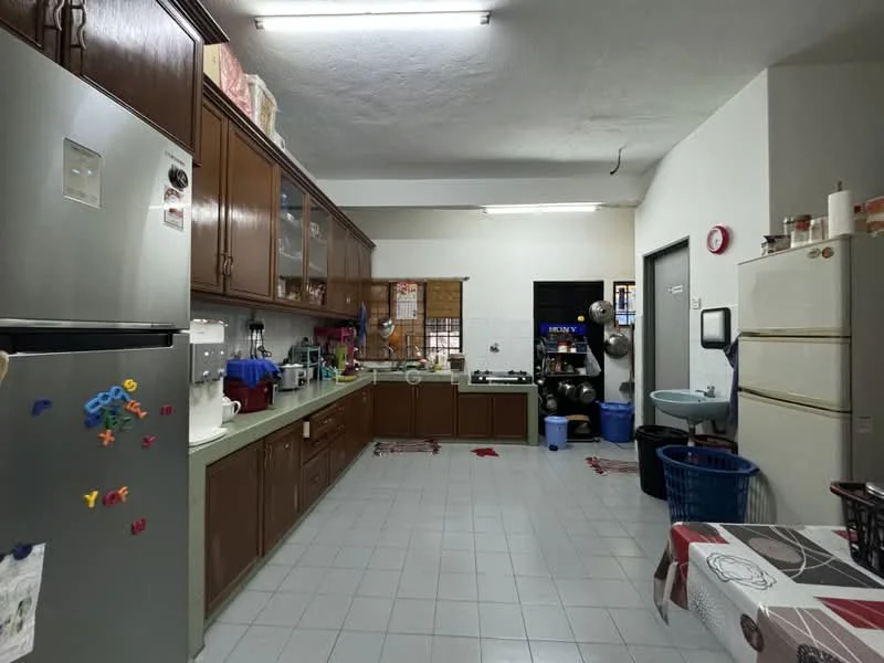 Kitchen features: brown wooden cabinetry, green countertop, stainless-steel fridge, freestanding white fridge, built-in oven, microwave, sink with faucet, wall-mounted shelves, tile flooring, ceiling lights, laundry basket, kitchen table with tablecloth.