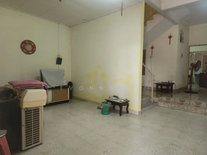 Living features: cream painted walls, tile flooring, window with sheer curtains, air conditioning unit, wooden coffee table, small side table, staircase leading to upper floor, decorative wall clock.
