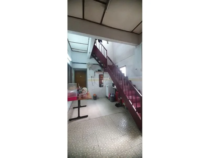Room features: staircase with red railing, white walls, exposed ceiling beams, tile flooring, open space, window for natural light, air conditioning unit, utility area with appliances, table with chairs, decorative items on floor.