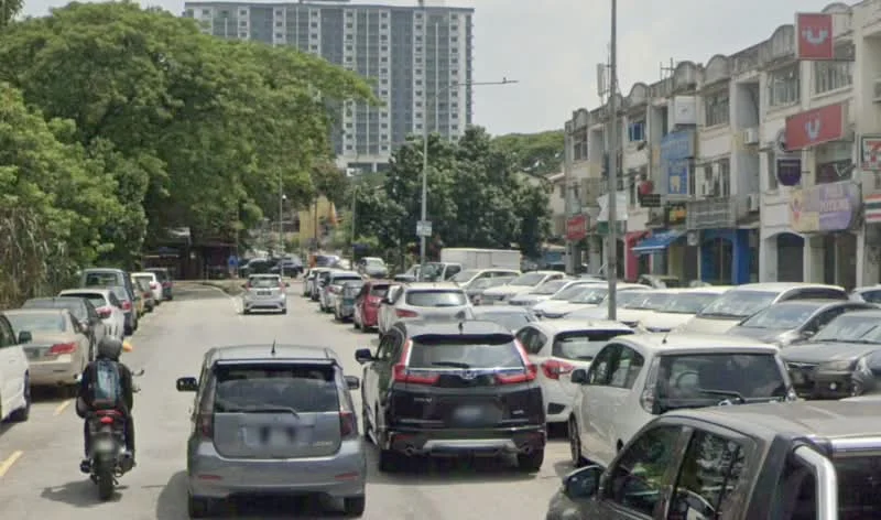 Exterior type: low-rise apartment block; features: street view with parked cars, surrounded by greenery, commercial shops visible, multiple storey buildings in background, paved road, urban setting; style: modern.
