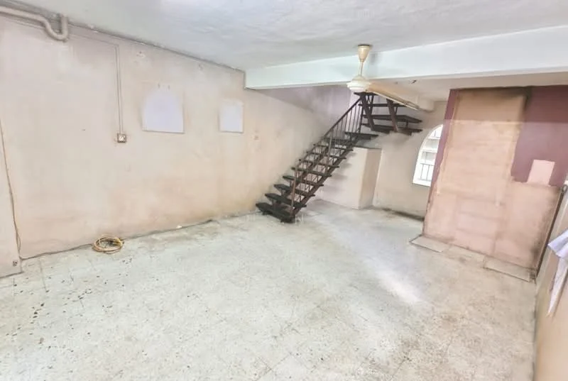 Room features: staircase with wooden steps, plain white walls, textured ceiling, tile flooring, exposed electrical wiring, no visible furniture, large open space, natural light from windows; style: minimalist.