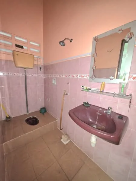 Bathroom features: pink tiled walls, brown sink, wall-mounted mirror, shower head, toilet, floor tiles, tiled shower area, soap holder, toilet roll holder.