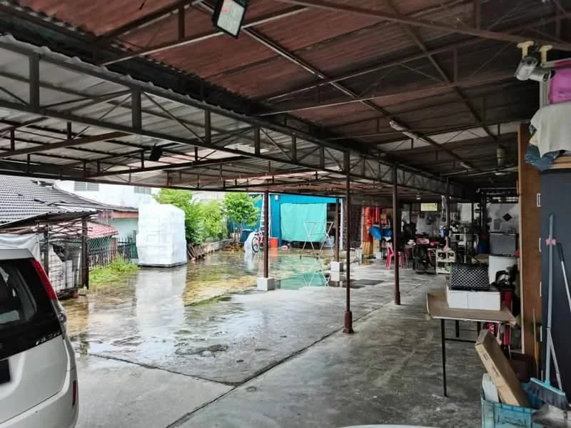 Exterior type: covered parking; features: metal roof, concrete flooring, open-air structure, multiple parking bays, surrounding greenery, water drainage visible, adjacent residential buildings; style: modern.