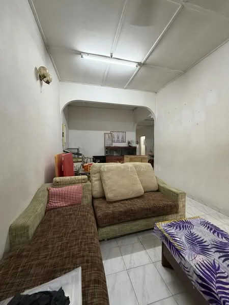 Living features: white painted walls, tile flooring, sofa with fabric upholstery in beige, sectional sofa with brown fabric, coffee table with floral pattern, wall-mounted light fixture, arched doorway, open layout to kitchen area.