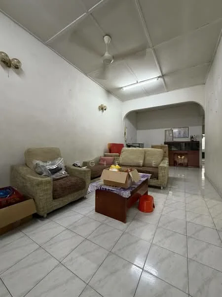 Living features: cream painted walls, white tiled flooring, 5-blade ceiling fan, 2-seater fabric sofa in beige, 3-seater fabric sofa in beige, wooden coffee table, decorative wall sconces, open layout to kitchen, box of items on floor, cardboard boxes, kitchen area visible in background.