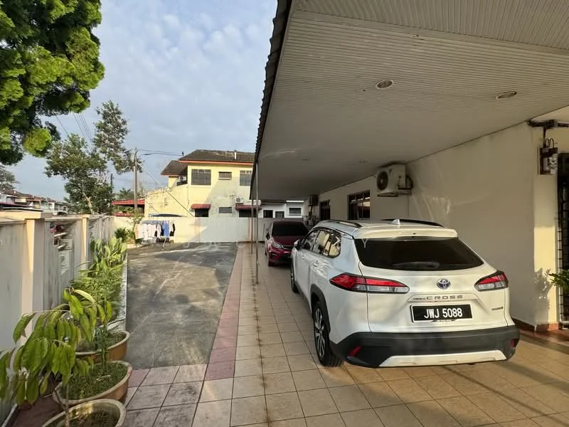 Exterior type: detached bungalow; features: paved driveway, two parked cars, white painted facade, single-storey, manicured plants in pots, covered porch, exterior wall-mounted air conditioning unit, laundry area visible in background, surrounded by greenery; style: modern.