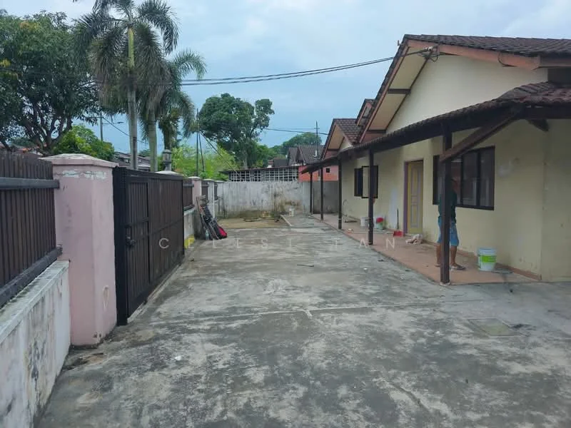 Exterior type: semi-detached house; features: paved driveway, fenced perimeter, single-storey, gabled roof, exposed concrete surface, mature palm trees, outdoor space, adjacent to residential area; style: traditional.