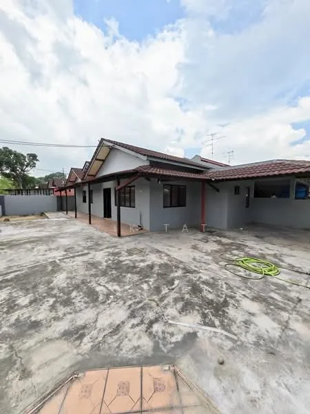 Exterior type: detached bungalow; features: grey painted facade, pitched tile roof, single-storey, concrete flooring, manicured lawn area, surrounded by low fencing, multiple windows, outdoor space, visible utility connections, driveway area; style: modern.