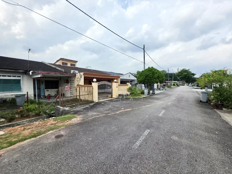 Exterior type: linked terrace house; features: yellow painted facade, gated entrance with decorative gate, paved driveway, manicured lawn, mature trees, street view, surrounded by residential houses, visible utility poles, sidewalks, garden planters, open space in front; style: traditional.