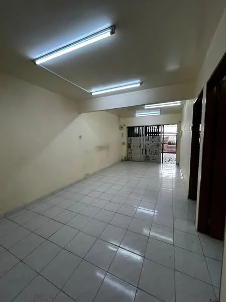 Room features: white painted walls, glossy white ceiling, fluorescent lighting, white tiled flooring, metal security grille door, large windows, open layout, no visible furniture; style: minimalist.