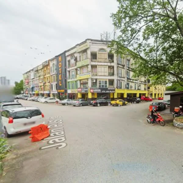 Exterior type: low-rise apartment block; features: multi-storey building, colorful facade, ground floor retail spaces, balconies on upper floors, signage for hotel, parking area in front, surrounding trees, street view, road access, visible vehicles; style: modern.