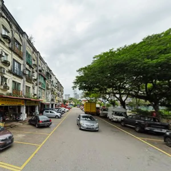 Exterior type: shophouse; features: two-storey shophouses, balconies with wrought iron railings, ground floor retail spaces, trees lining the street, asphalt road, parking spaces visible, urban setting, cloudy sky; style: traditional.