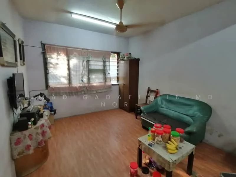 Living features: green fabric sofa, wooden coffee table, TV on wall-mounted bracket, wooden cabinet, laminate flooring, ceiling fan, curtains on windows, decorative items on table, wall-mounted artwork, light fixture on ceiling.
