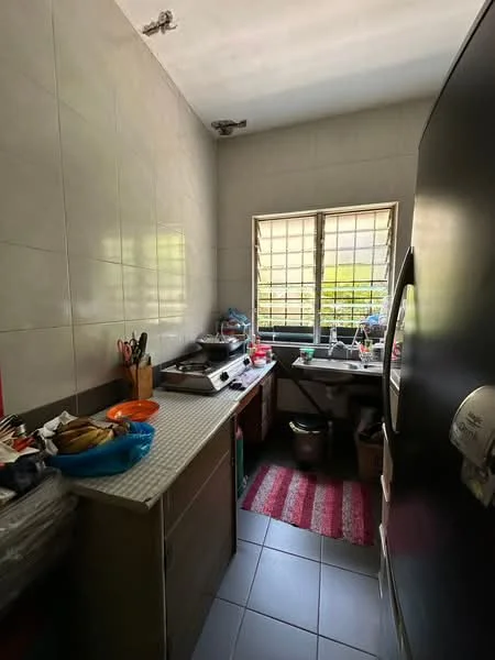 Kitchen features: grey tiled walls, white tiled flooring, single-bowl stainless-steel sink, chrome pull-down faucet, countertop with patterned surface, wooden cabinetry, refrigerator, kitchen utensils on countertop, window with metal grille, red area rug, stove, various food items on countertop; view: garden.