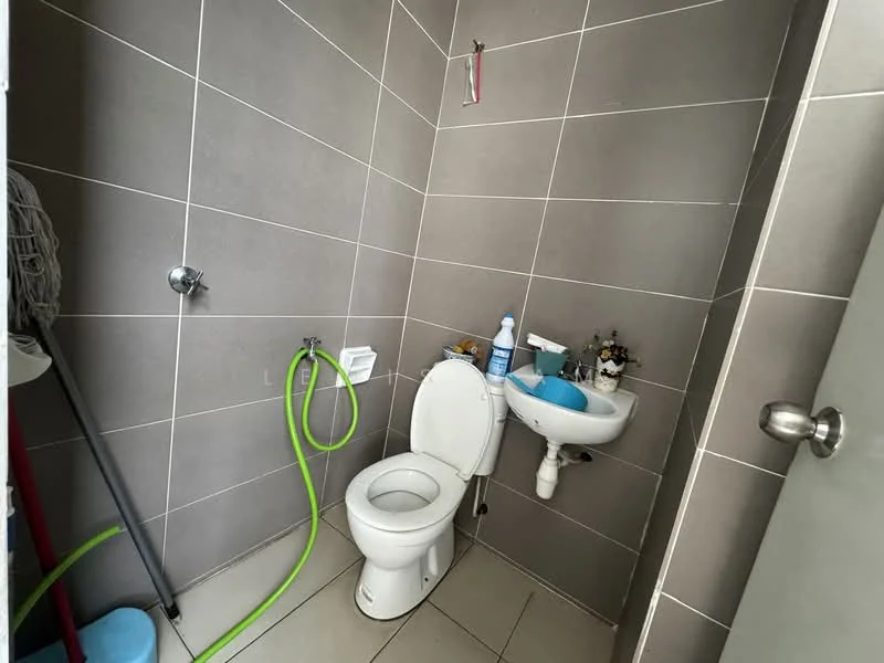 Bathroom features: grey tiled walls, white toilet, white sink, chrome faucet, green hose, floor tiles, toilet paper holder, small shelf with toiletries; style: modern.