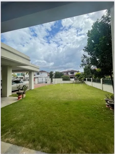 Exterior type: detached bungalow; features: manicured lawn, paved walkway, fence surrounding the property, mature trees, outdoor planters, car parking area, single-storey structure, cloudy sky; style: modern.