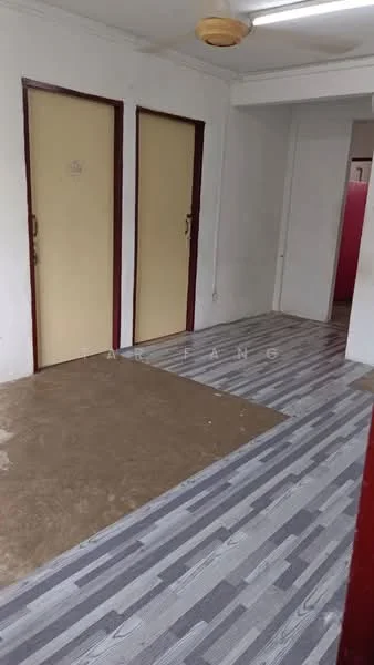 Room features: light grey laminate flooring, white painted walls, two wooden doors with cream panels, ceiling light fixture, exposed ceiling, corner wall with red paint, concrete flooring in part of the room.