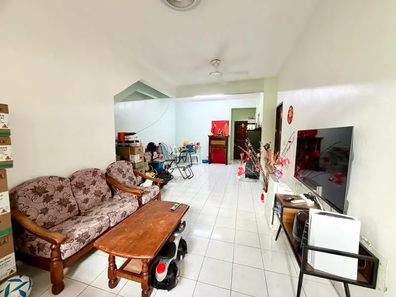 Living features: floral-patterned 3-seater sofa, wooden coffee table, white tiled flooring, wall-mounted TV, TV console, ceiling fan, decorative plants, boxes stacked against the wall, dining table with chairs in background, green wall paint in background.