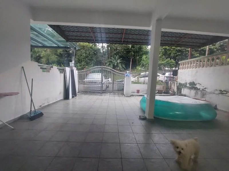 Exterior features: covered patio area, grey tiled flooring, white painted walls, metal gate, green inflatable pool, outdoor space with plants, sweeping broom, fenced perimeter.
