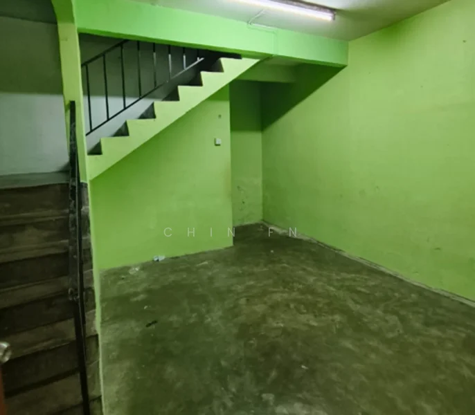 Room features: green painted walls, concrete flooring, staircase with metal railing, fluorescent ceiling light.