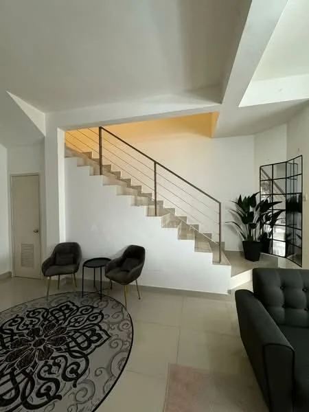 Living features: grey fabric sofa, 2 accent chairs in dark fabric, round coffee table with black legs, area rug with intricate pattern, staircase with metal railing, white painted walls, tile flooring, large potted plant, decorative screen divider; style: modern.