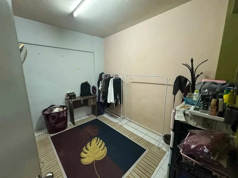Room features: light beige painted walls, white tiled flooring, ceiling light fixture, clothes rack, laundry basket, small shelf unit, area rug with leaf pattern, folding chair; style: minimalist.