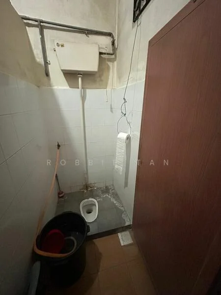 Bathroom features: white tiled walls, grey tiled flooring, toilet, wall-mounted water tank, exposed plumbing, bucket, mop, hanging toilet paper holder.