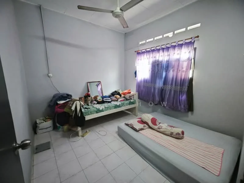 Bedroom features: light grey painted walls, white ceiling, white tiled flooring, single bed, mattress on floor, bedside rug, window with sheer and patterned curtains, mirror on dresser, clothes on bed, clothes on floor, ceiling fan.