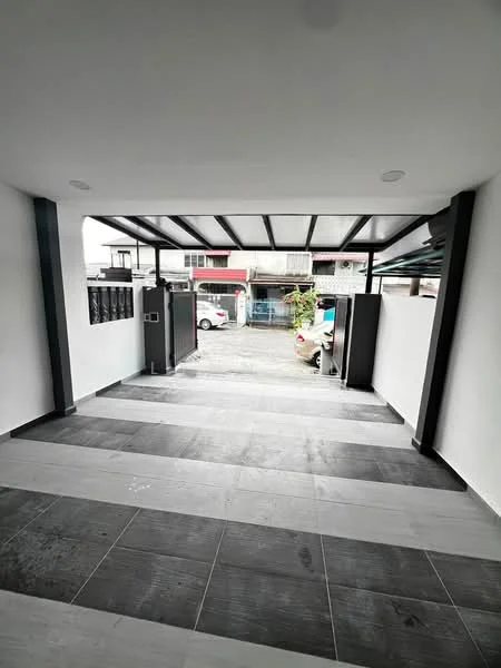 Exterior type: car porch; features: covered car porch with metal roofing, grey and white tiled flooring, two vertical gates, concrete walls, exposed brick wall, surrounding white walls, driveway leading to street, landscaped area visible, parking space for multiple vehicles; style: modern.