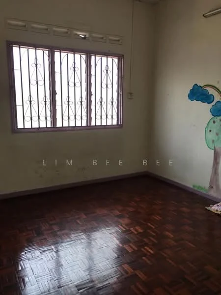 Room features: wooden flooring, painted walls in light colour, window with metal grille, corner wall with mural of tree, ceiling light fixture, no visible furniture, empty space.