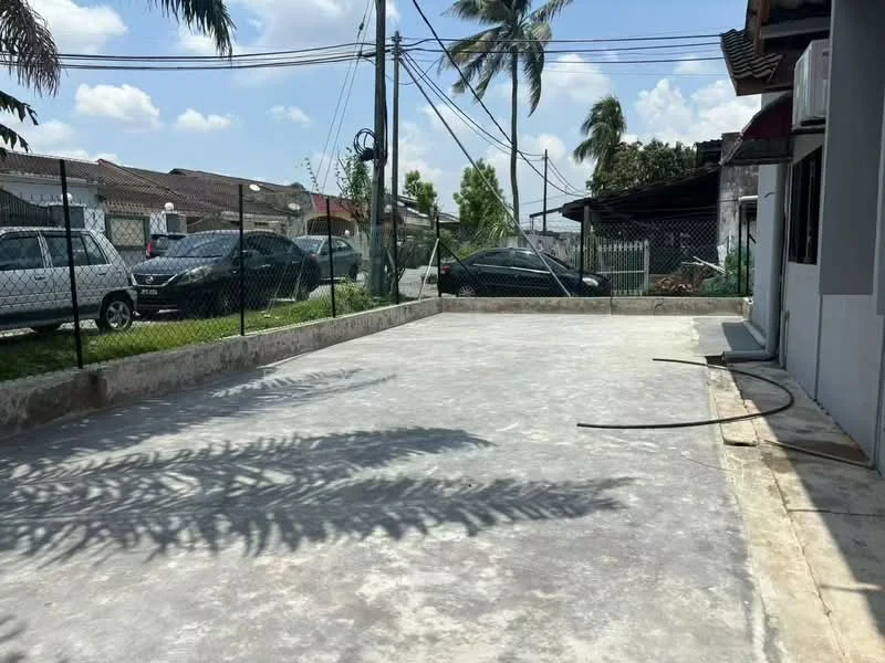 Exterior features: concrete parking area, fenced perimeter, paved driveway, surrounding greenery, multiple parked cars, overhead power lines, palm trees, clear blue sky.