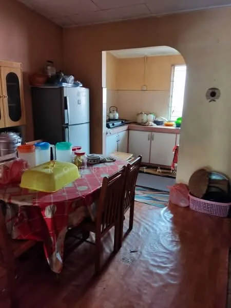Kitchen features: wooden dining table with chairs, red tablecloth, stainless-steel fridge, white cabinetry, sink with faucet, countertop with kitchen appliances, window with natural light, wooden flooring, various kitchen utensils and containers.