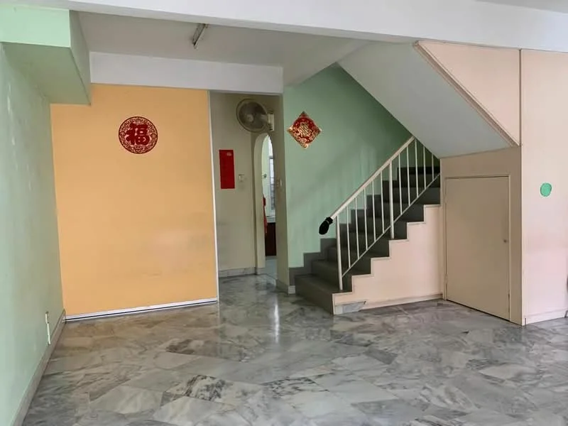 Room features: marble flooring, green painted walls, orange painted walls, staircase with metal railing, built-in cabinet, wall-mounted fan, doorway leading to another room, decorative wall elements.