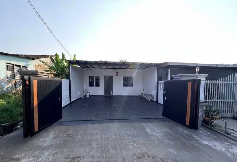 Exterior type: detached bungalow; features: double-gate entrance, paved driveway, covered porch area, exterior wall with white paint, flat roof, outdoor lighting fixtures, manicured landscaping, surrounding greenery; style: modern.