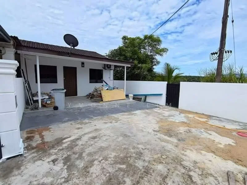 Exterior type: detached bungalow; features: concrete driveway, white painted walls, flat roof, satellite dish, outdoor space with debris, fenced perimeter, mature trees in background, power lines visible; style: modern.