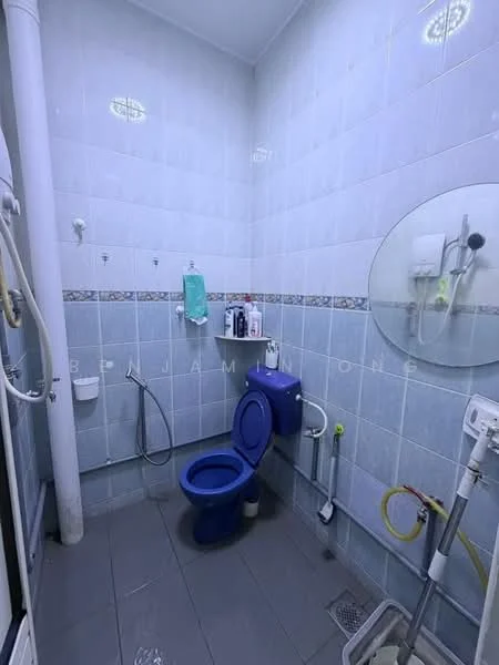 Bathroom features: blue toilet, white sink, shower with handheld showerhead, tiled walls with blue and white pattern, grey tile flooring, mirror, toilet paper holder, soap dispenser, wall-mounted toiletries rack, shower curtain rod.
