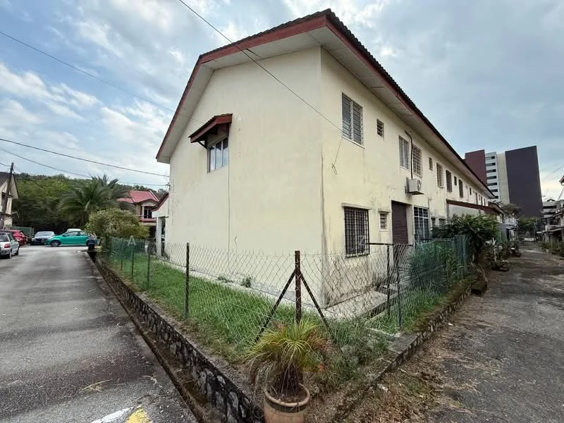 Exterior type: linked terrace house; features: cream painted facade, single-storey, gated perimeter fence, manicured lawn, windows with security grills, red pitched tile roof, surrounded by greenery, driveway with interlocking pavers; style: traditional.