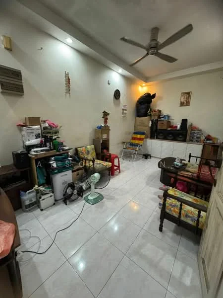 Room features: white painted walls, glossy white tile flooring, ceiling fan, wall-mounted air conditioning unit, various boxes and storage items, small table with chairs, decorative wall art, floor fan, wooden furniture, colorful upholstery on seating.
