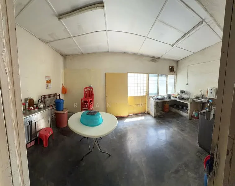 Kitchen features: white painted walls, exposed concrete ceiling, grey polished concrete flooring, single-bowl stainless-steel sink, chrome pull-down faucet, kitchen cabinets with metal handles, countertop with space for appliances, window with grid pattern, table with blue basin, red plastic chairs, kitchen appliances visible.