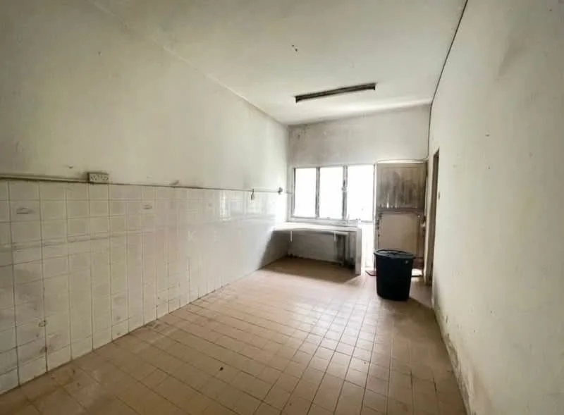 Room features: white painted walls, tile flooring, single window with no treatments, empty countertop, sink area with no visible sink, no visible appliances, plain ceiling, door leading outside.