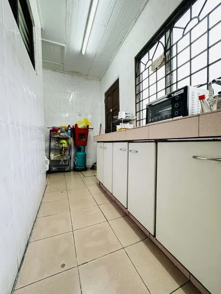 Kitchen features: white laminate cabinetry, pink tiled countertop, ceramic tile flooring, stainless-steel microwave, kitchen sink, window with metal grille, wall tiles with white finish, appliance storage cart, cleaning supplies, kitchen utensils.
