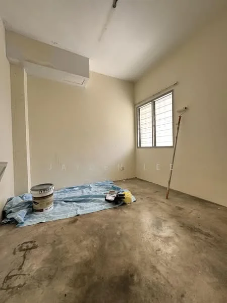 Room features: plain white walls, concrete flooring, window with horizontal slats, wall-mounted air conditioning unit, paint bucket, paint roller, blue tarp on floor, wooden stick.