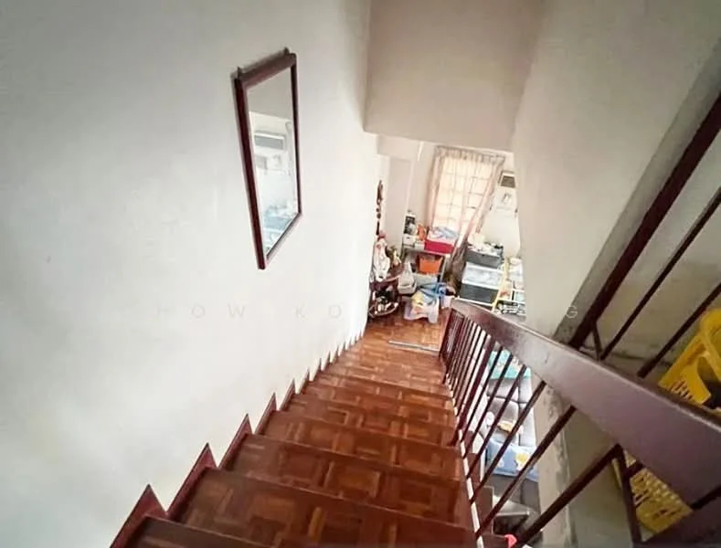 Room features: wooden staircase with handrail, parquet wood flooring, white painted walls, framed mirror on wall, natural light from window, cluttered space at the bottom of the stairs.