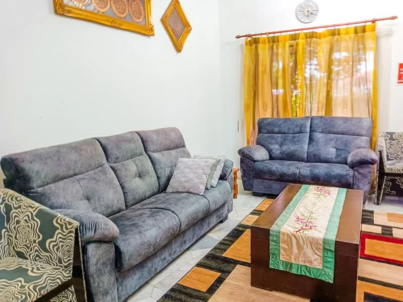 Living features: 2-seater fabric sofa in grey, 3-seater fabric sofa in grey, coffee table with dark wood finish, area rug with geometric pattern, curtains in yellow sheer fabric, wall clock, framed artwork on wall, tile flooring; style: contemporary.