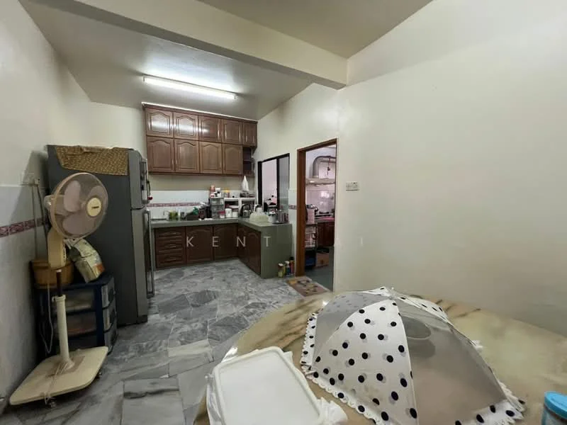 Kitchen features: grey marble flooring, white painted walls, wooden cabinetry in dark brown, double-bowl stainless-steel sink, chrome pull-down faucet, built-in oven, freestanding refrigerator, ceiling fan, window with sheer curtains, countertop with food preparation area, kitchen island, wall-mounted shelves.