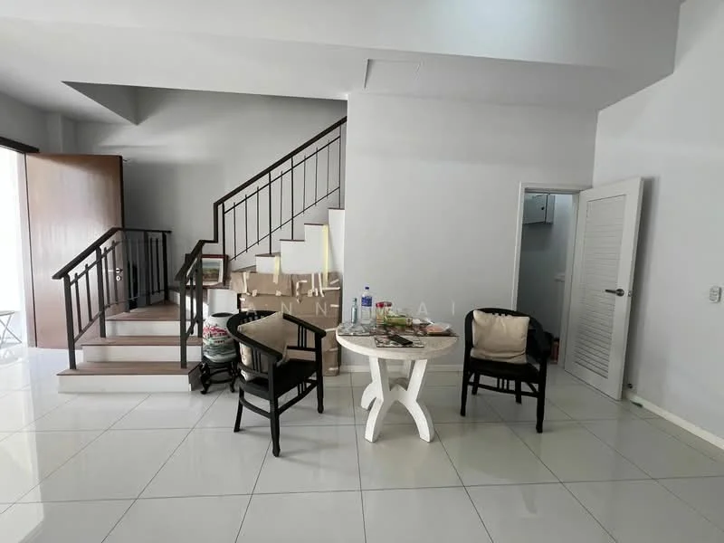 Room features: white painted walls, glossy tile flooring, staircase with wooden railing, round dining table, two black chairs, decorative plants, door leading to another room, door leading outside; style: modern.