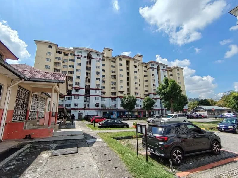 Exterior type: mid-rise condominium; features: yellow painted facade, multiple storeys, balconies on upper floors, landscaped green area, parking spaces visible, surrounded by trees, driveway with interlocking pavers; style: modern.